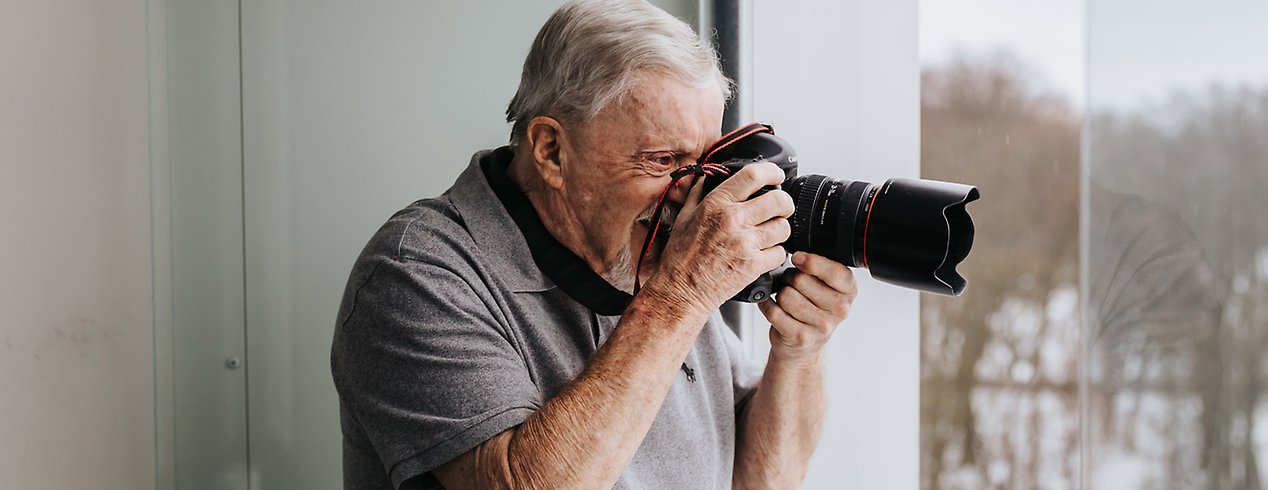 Äldre man med en kamera i högsta hugg.