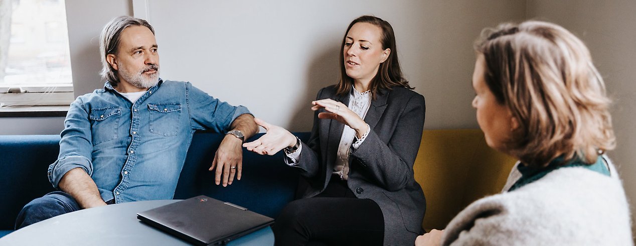 En man och två kvinnor sitter ner och diskuterar.