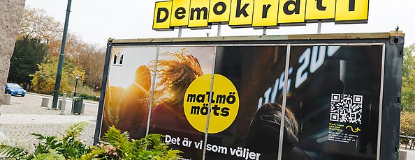 En omgjord container med "reklam" och information om Malmö möts. På taket står det "Demokrati". 