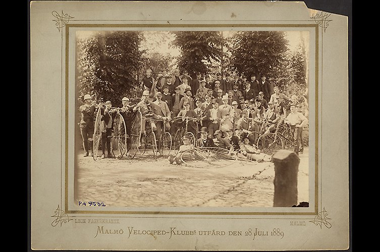 Gulnat fotografi av ett gäng män uppställda med sina cyklar.
