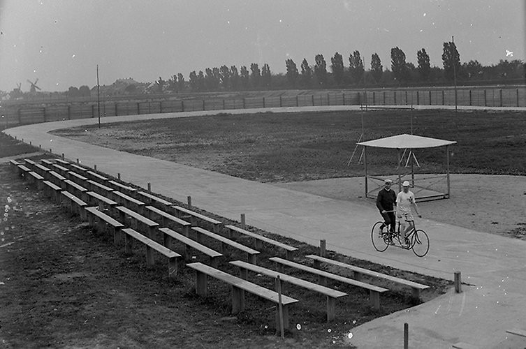 Tom bana med två cyklister på en tandemcykel. Svartvitt foto.