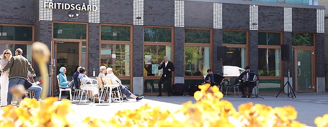 Fritidsgården i Holma, människor sitter utanför i solen och lyssnar på musik.