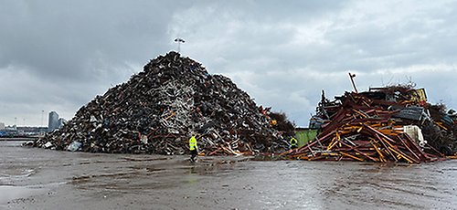 En inspektör står på ett industriområde med en hög avfall i bakgrunden