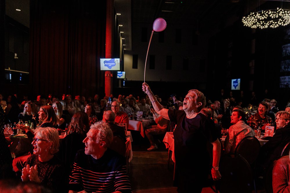 En person viftar med en rosa ballong i ett folkhav